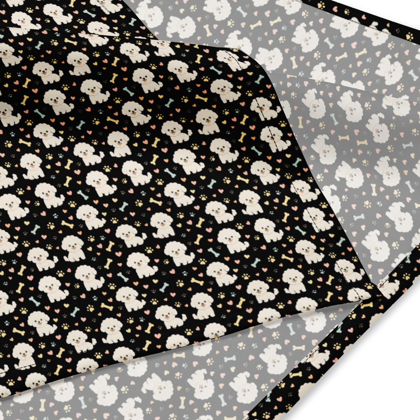 Close-up of black bandana fabric with cute Bichon Frise dog pattern, paw prints, hearts, and bones design