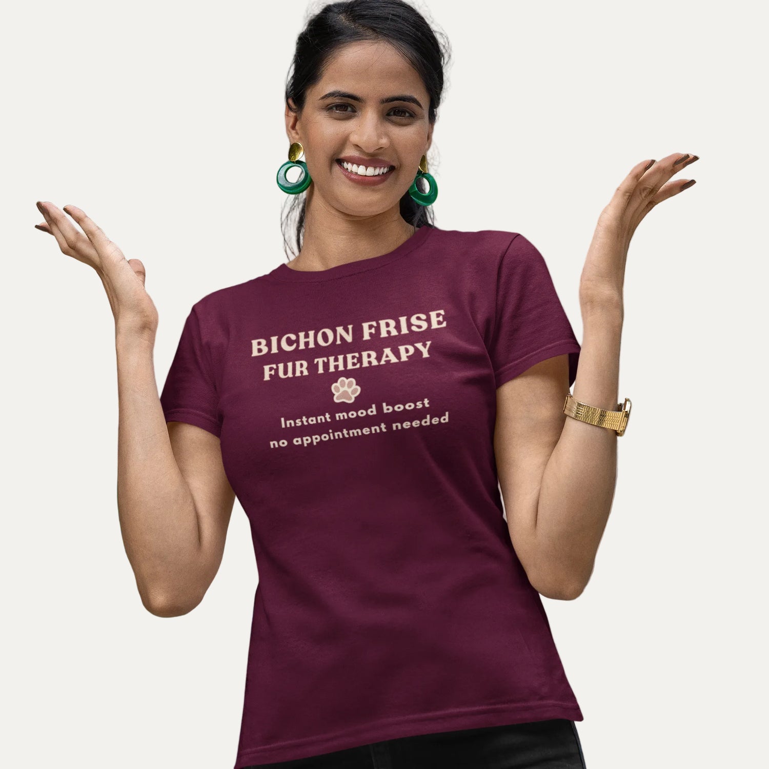 Smiling woman wearing a burgundy Bichon Frise Fur Therapy t-shirt with ‘Instant Mood Boost, No Appointment Needed’ slogan, casual outdoor setting with colorful mural background.