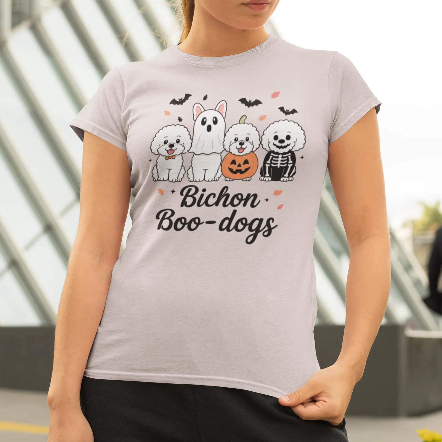 Woman wearing a Halloween Bichon Boo-dogs t-shirt featuring four cute Bichon Frise dogs in spooky costumes
