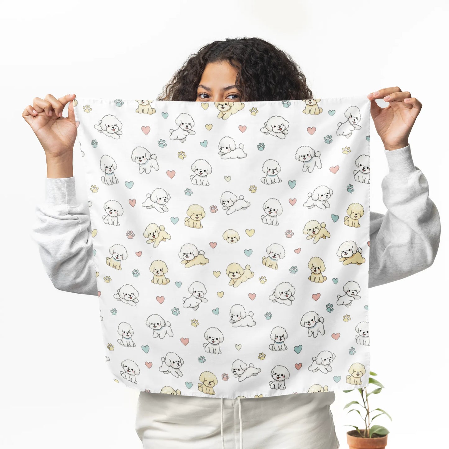 Smiling woman holding up a cream bandana with a cute Bichon Frise, pastel hearts and paw prints pattern – stylish dog lover accessory mockup
