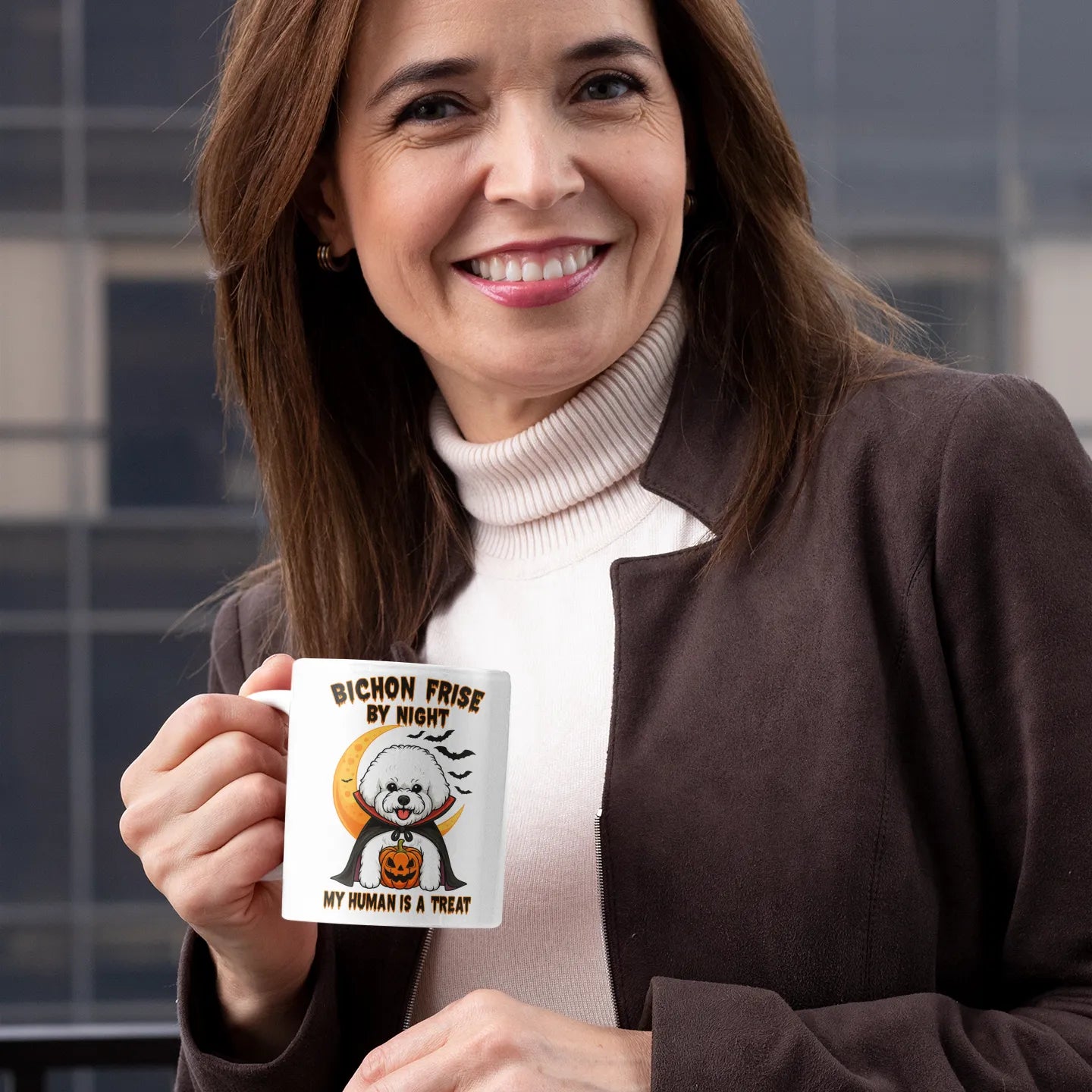 Smiling woman holding a white Halloween coffee mug with a Bichon Frise vampire design and the text "Bichon Frise by Night – My Human is a Treat