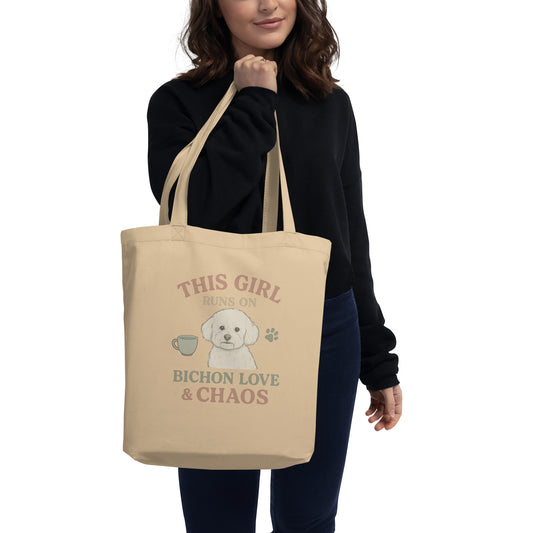 Woman holding beige eco tote bag with funny Bichon Frise dog print and text This Girl Runs on Bichon Love & Chaos