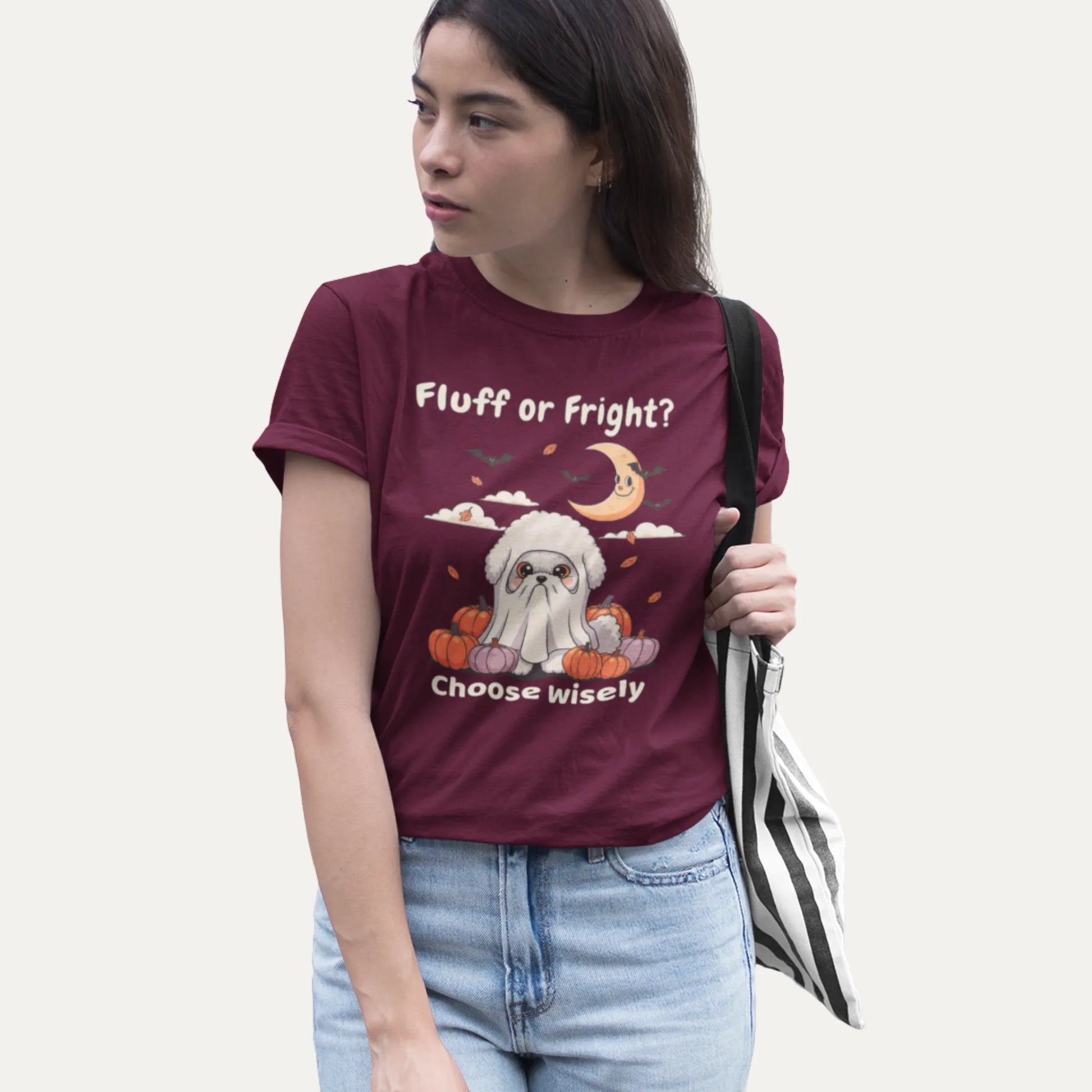 Funny Bichon Frise Halloween t-shirt with ghost costume design, shown on a burgundy shirt worn by a woman with tote bag.