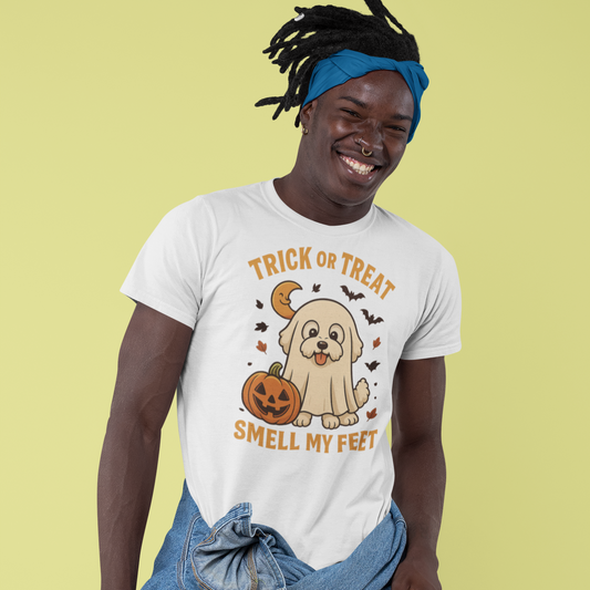 Smiling man wearing a white Halloween t-shirt featuring a cute Bichon Frise dressed as a ghost with a pumpkin and the text 'Trick or Treat Smell My Feet'
